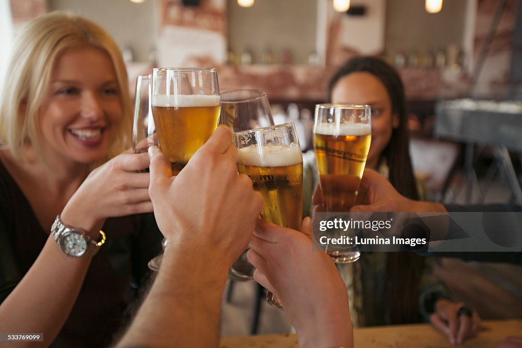 Friends toasting with beer in cafe