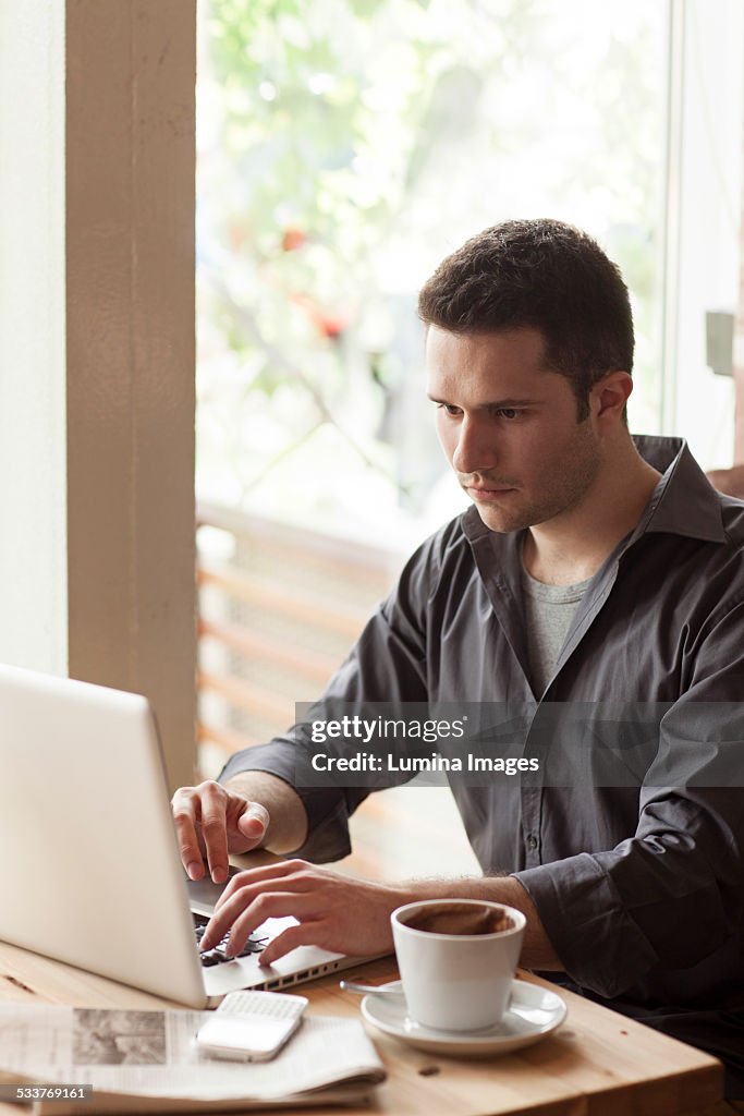 Man using laptop with cup of coffee in cafe