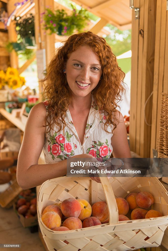 Caucasian woman basket of peaches at farmers market