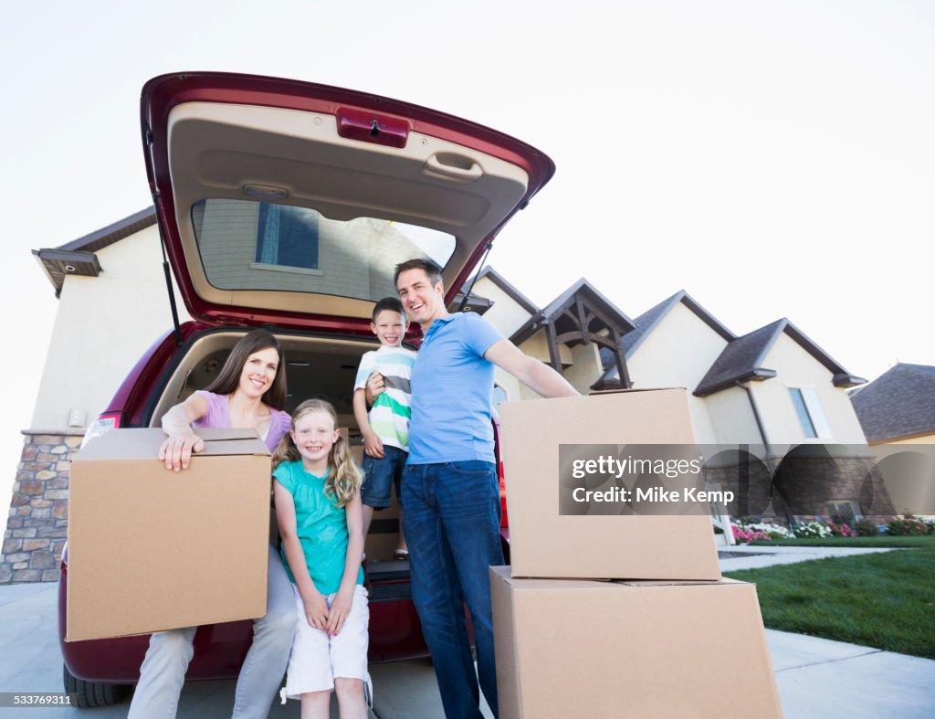 Caucasian family unpacking cardboard boxes from car