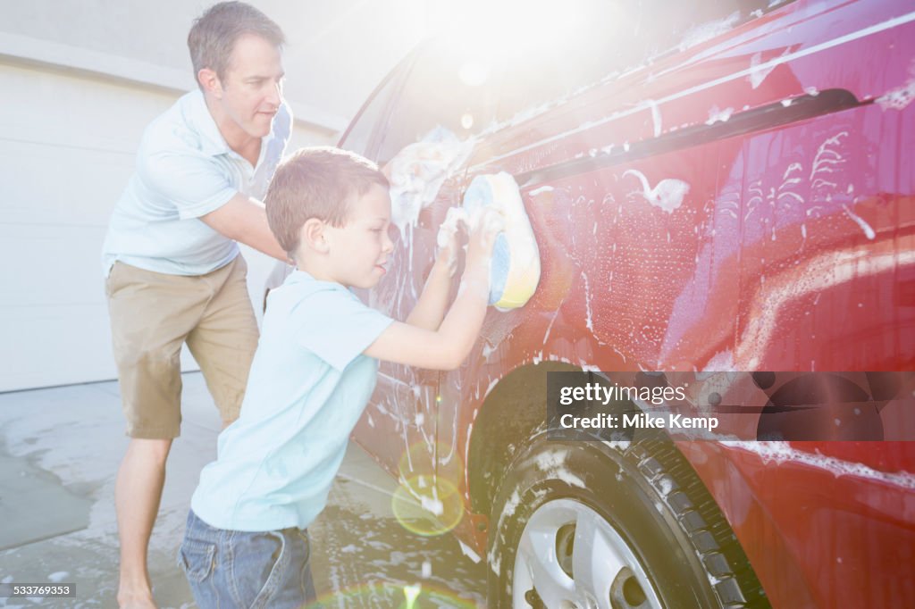 Caucasian father and son washing car in driveway