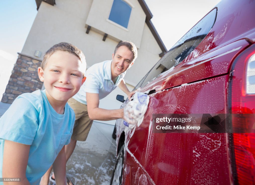 Caucasian father and son washing car in driveway