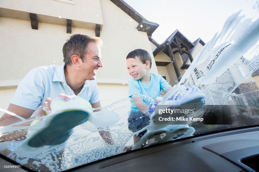 Caucasian father and son washing car windshield