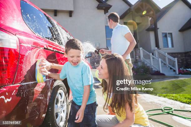 caucasian family washing car in driveway - family car at home stock-fotos und bilder