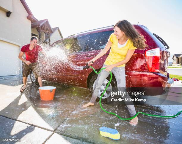 caucasian couple playing while washing car in driveway - couples showering together 個照片及圖片檔