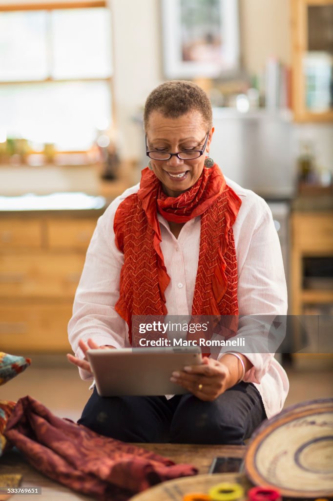 Older mixed race woman using digital tablet in home office