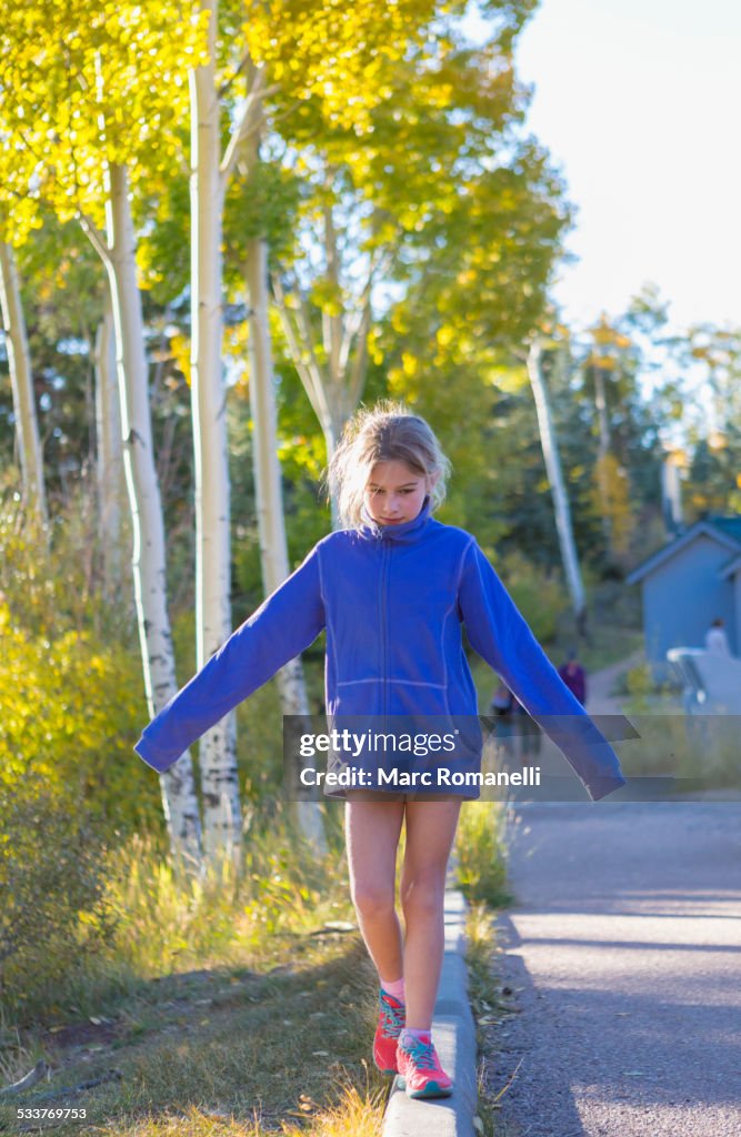 Caucasian girl balancing on concrete curb