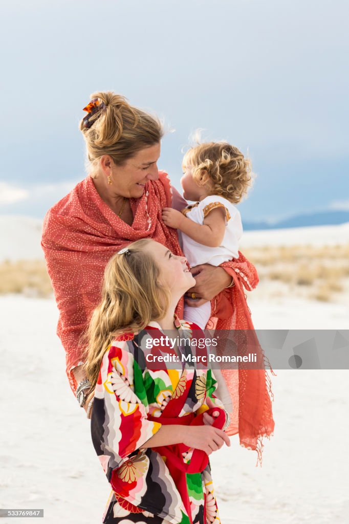 Caucasian mother and children laughing on sand dune