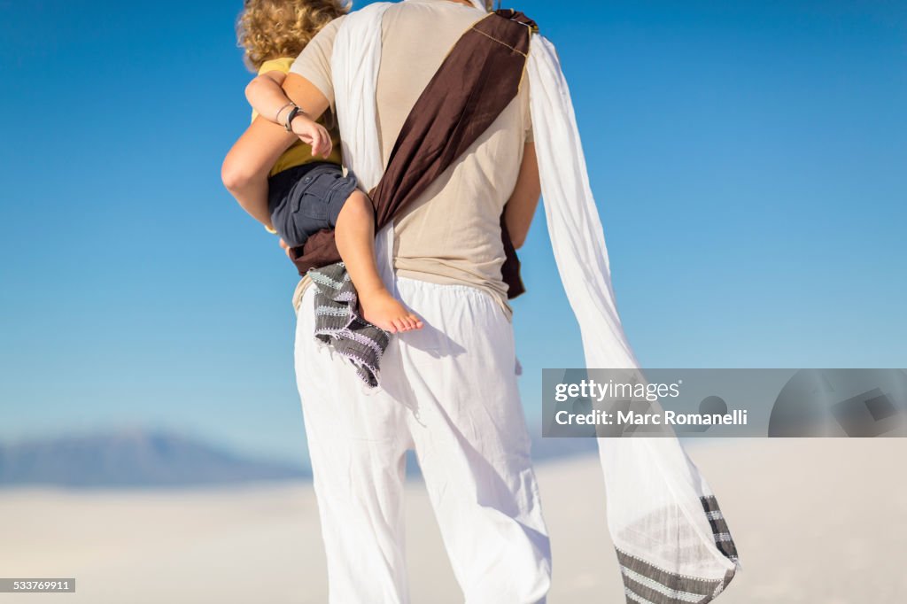 Caucasian mother holding son on sand dune