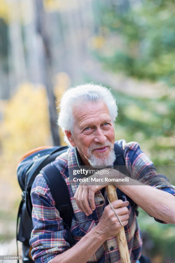 Caucasian hiker leaning on walking stick in forest
