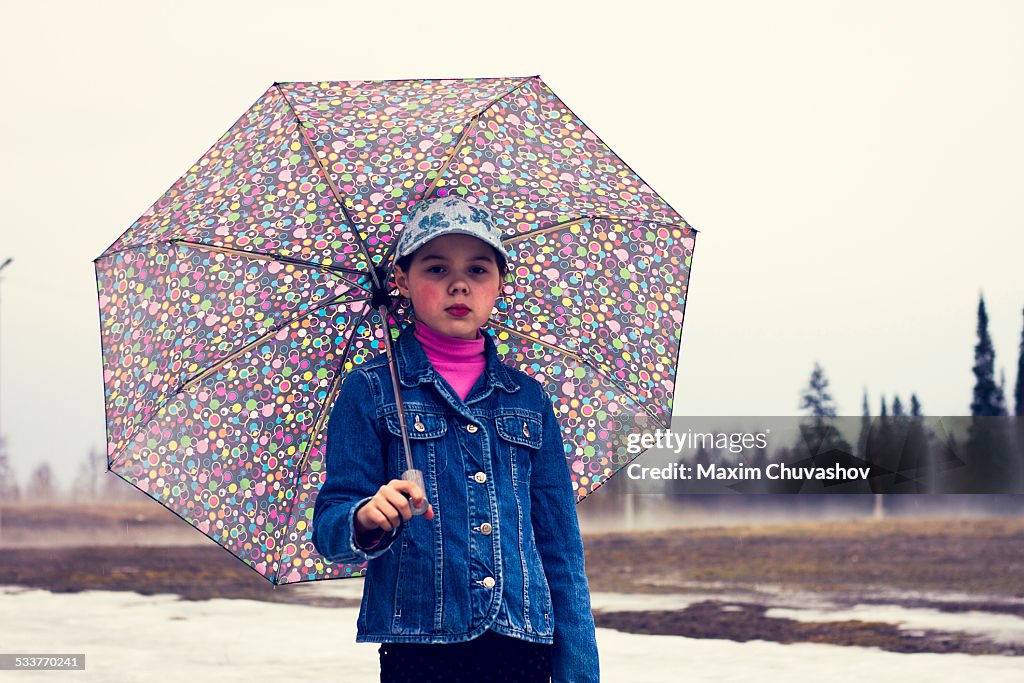 Caucasian girl walking under umbrella in snowy field