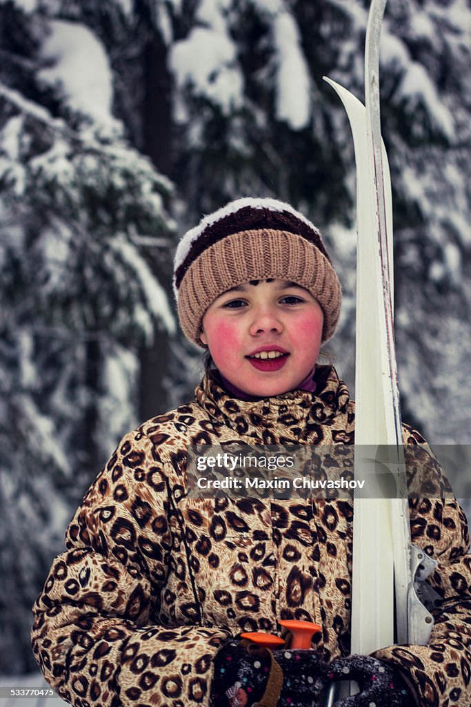 Caucasian girl carrying skis in forest