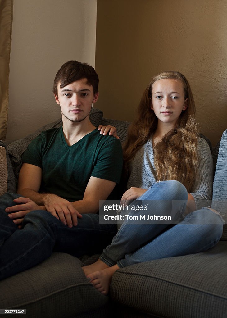 Caucasian brother and sister smiling on sofa