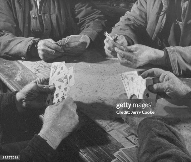 The hands of four men, holding cards, as they play a cribbage game, Marysville, Iowa, 1946.