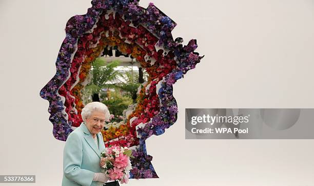 Queen Elizabeth II is pictured next to a floral exhibit by the New Covent Garden Flower Market, which features an image of the Queen, at Chelsea...