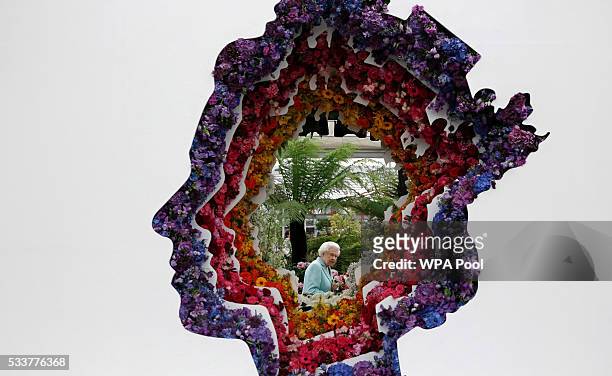 Queen Elizabeth II is pictured through a gap in a floral exhibit by the New Covent Garden Flower Market, which features an image of the Queen, at...