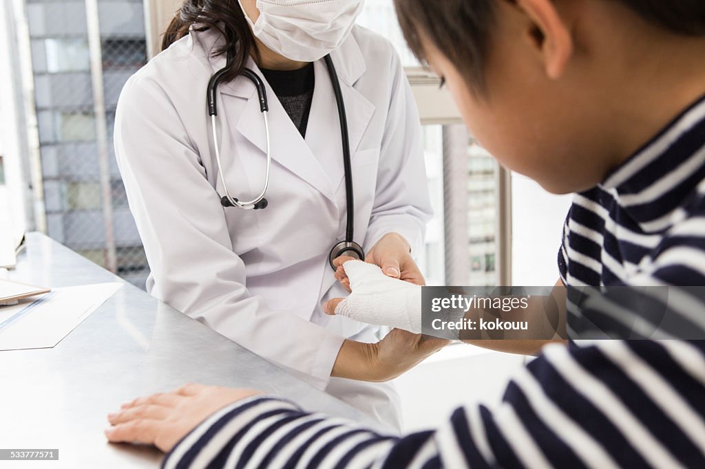 Doctor putting a bandage on boy's wrist