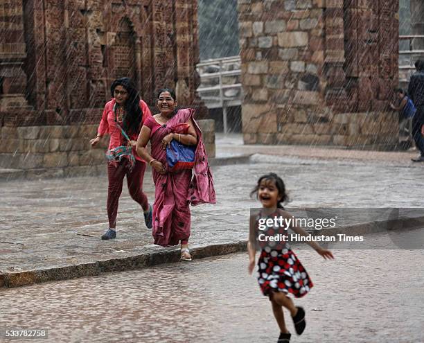 Family enjoys pleasant weather during rain showers after a hot and humid afternoon in the national capital at Qutub Minar on May 23, 2016 in New...