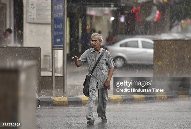 An elderly man caught in rain at Connaught Place on May 23, 2016 in New Delhi, India. Sudden rains brought respite for people in capital after a hot...