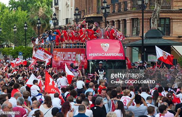 Sevilla's players parade on top of a bus along a street of Sevilla on May 23, 2016 to celebrate their third consecutive cup of the UEFA Europa League...