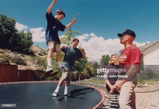 Boxing referee Mills Lane , a Washoe County district court judge, with his wife Kaye watching their sons Tommy and Terry play on trampoline in yard...