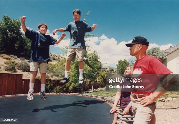 Boxing referee Mills Lane , a Washoe County district court judge, with his wife Kaye watching their sons Tommy and Terry play on trampoline in yard...