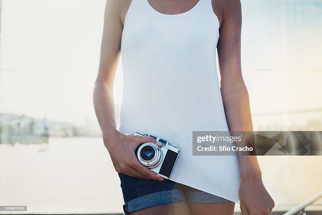 Young woman in blank sleeveless t-shirt with vintage camera