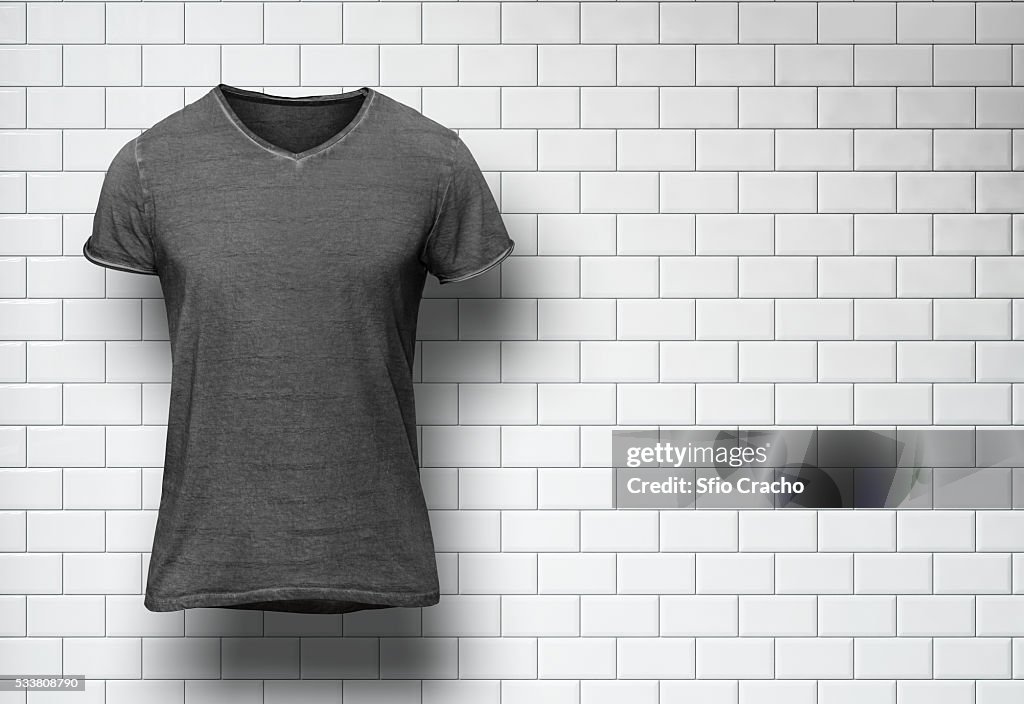 Blank t-shirt on white tile wall background