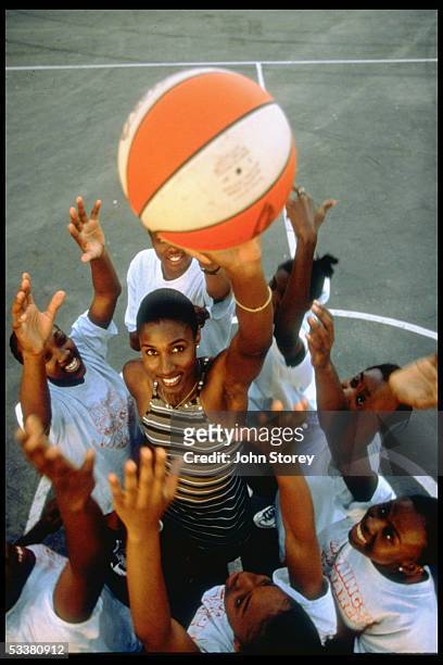 Star/model Lisa Leslie shooting hoops with young girls.