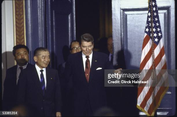 President Ronald with Reagan and Japan's Prime Minister Noboru Takeshita preparing to sign science and technology agreement during economic summit...