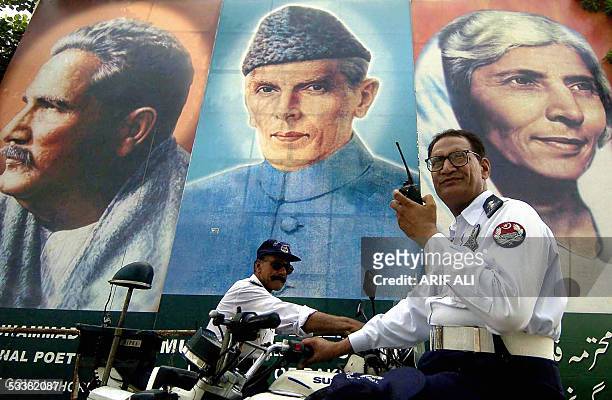Two Pakistani policemen guard a street standing in front of a portrait of the country's founder Mohammad Ali Jinnah along with his sister Fatima...