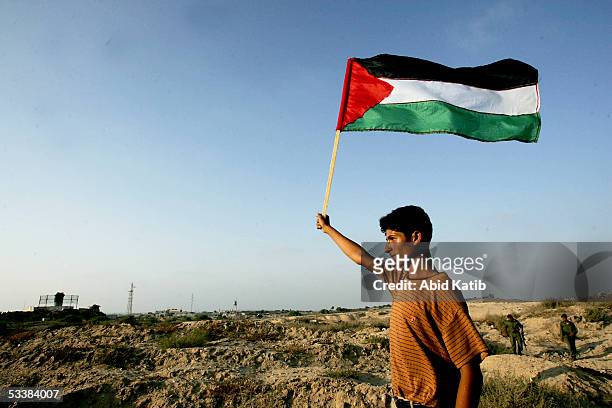 Palestinian youth waves a Palestinain national flag in front of the Israeli settlement of Navi Dakalem during early celebrations of Israel's imminent...