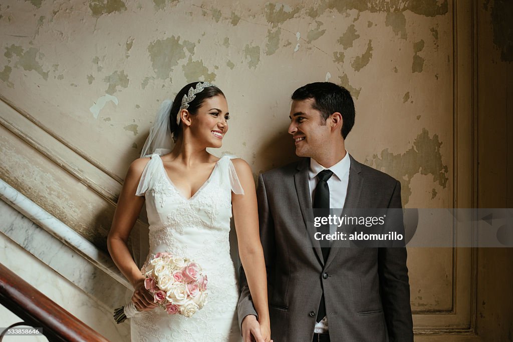 Hispanic newlyweds standing against a grunge wall
