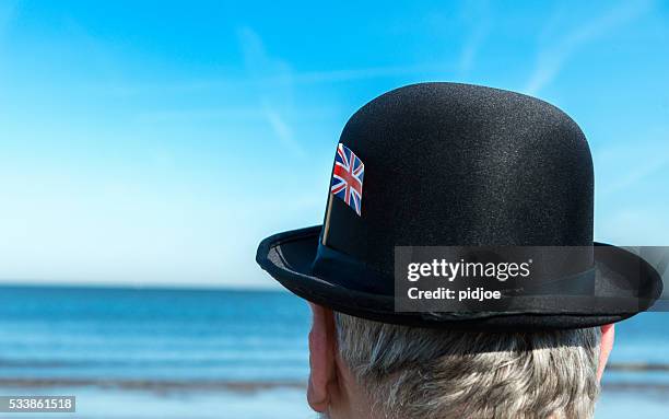 portrait of englishman standing on the beach, overlooking the sea - british man bowler hat stock pictures, royalty-free photos & images