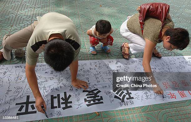 Chinese residents sign their names on a banner reading" Cherish Peace" during a signature activity to mark 60th anniversary of China's victory in the...