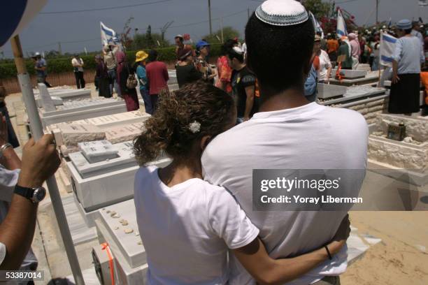 Vered Hazani hugs her husband Sahar as they stand next to the grave of her father Hanoh Sharabbi August 14, 2005 in Neve Dkalim, Gaza Strip. The...