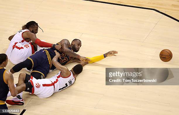 LeBron James of the Cleveland Cavaliers competes for a loose ball late in the game against DeMarre Carroll and Kyle Lowry of the Toronto Raptors in...