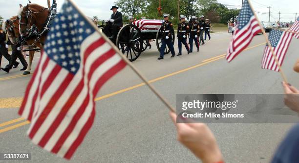 Mourners hold flags as the body of Lance Cpl. Timothy Bell Jr. Is taken to Lakota East High School for a memorial service August 14, 2005 in Liberty...