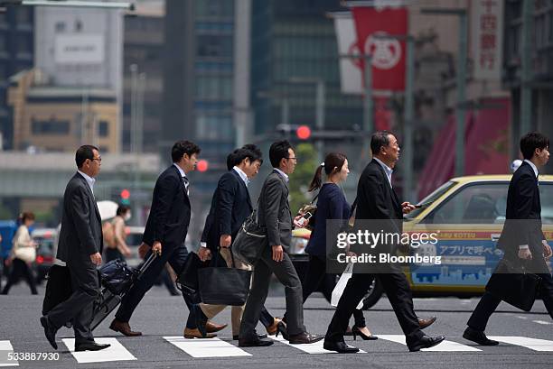 Office workers walk across an intersection in Tokyo, Japan, on Tuesday, May 24, 2016. Japan's service producer price index figures are scheduled to...