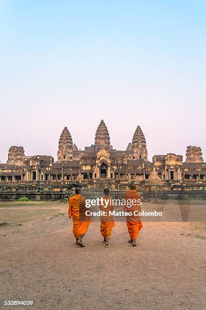 three buddhist monks walking to angkor wat temples - cambodia stock pictures, royalty-free photos & images