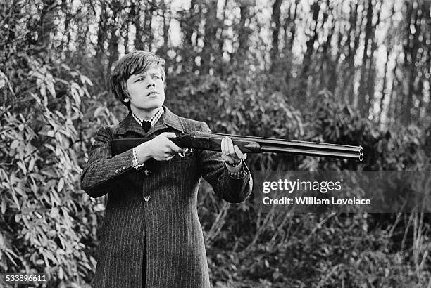 English singer-songwriter Peter Noone, of pop group Herman's Hermits, holding a shotgun, Kent, 17th February 1967.