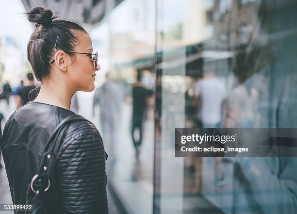 yooung woman looking at shop windows - window display stock pictures, royalty-free photos & images