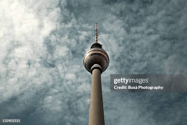 berlin's tv tower against a cloudy sky - berlin fernsehturm stock pictures, royalty-free photos & images