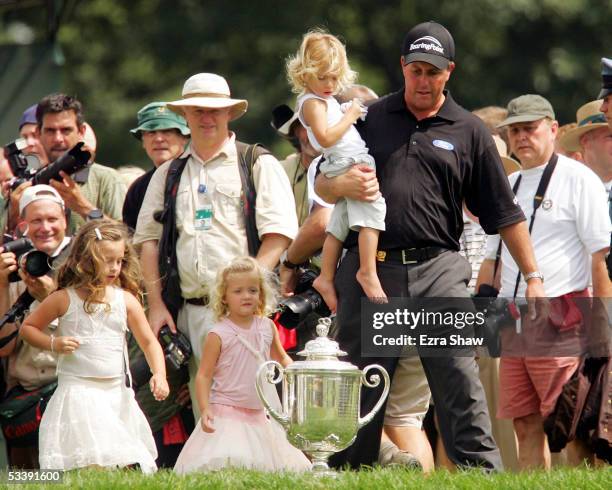 Phil Mickelson holds his daughter Evan, as his other daughters, Amanda and Sophia walk beside him in front of the Wanamaker Trophy after Mickelson...