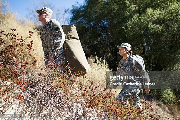army woman and man hiking up hill - military rucksack stock pictures, royalty-free photos & images
