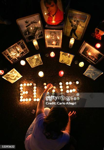 Girl lights candles during a vigil to mark the 28th anniversary of Elvis Presley's death during Elvis Week 2005 at Graceland August 15, 2005 in...