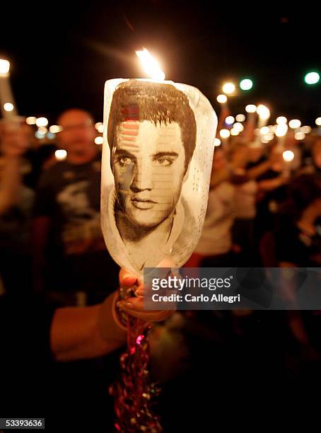 Woman displays an image of Elvis Presley during a candle-light vigil to mark the 28th anniversary of Elvis Presley's death during Elvis Week 2005 at...