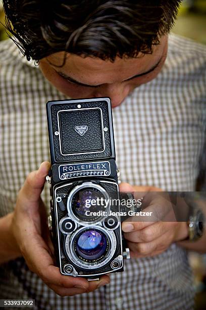 Man is holding a Rolliflex camera in a secondhand shop for cameras in Tokyo.