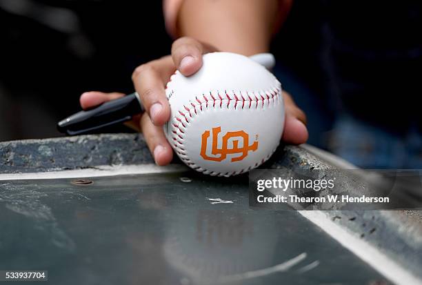 Detailed view of a fan holding a baseball with the San Francisco Giants logo on it, seeking autographs prior to the game against the Chicago Cubs at...