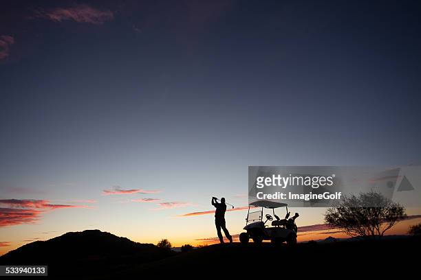 male caucasian golfer swinging a golf club with cart - desert twilight stock pictures, royalty-free photos & images